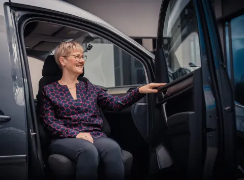 Moteris patogiai sėdasi į automobilį su pasukama sėdyne